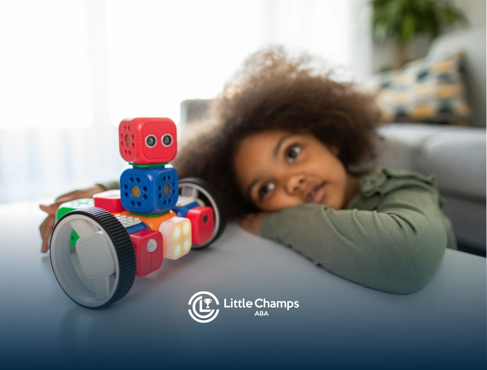 Autistic child resting head on table next to a robot toy during an in-home ABA therapy in Utah.