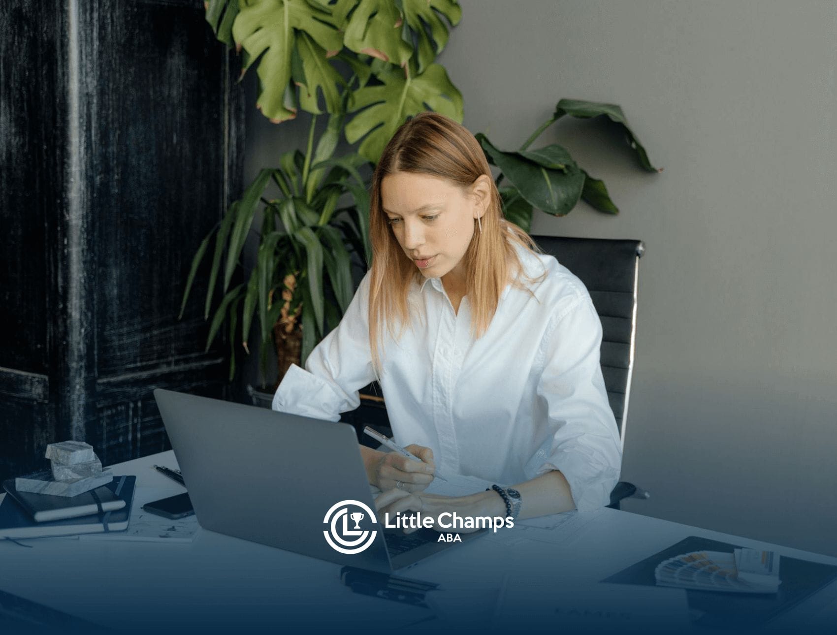 An RBT student studying on a laptop for RBT certification in a stylish office space with indoor plants in Utah.