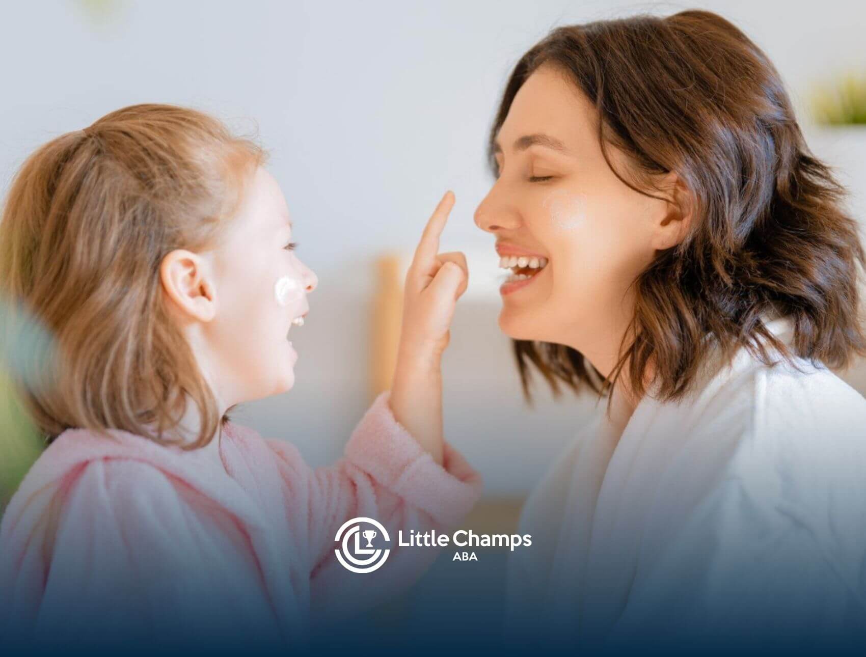 Smiling girl with autism playfully putting cream on a female ABA therapist's nose.