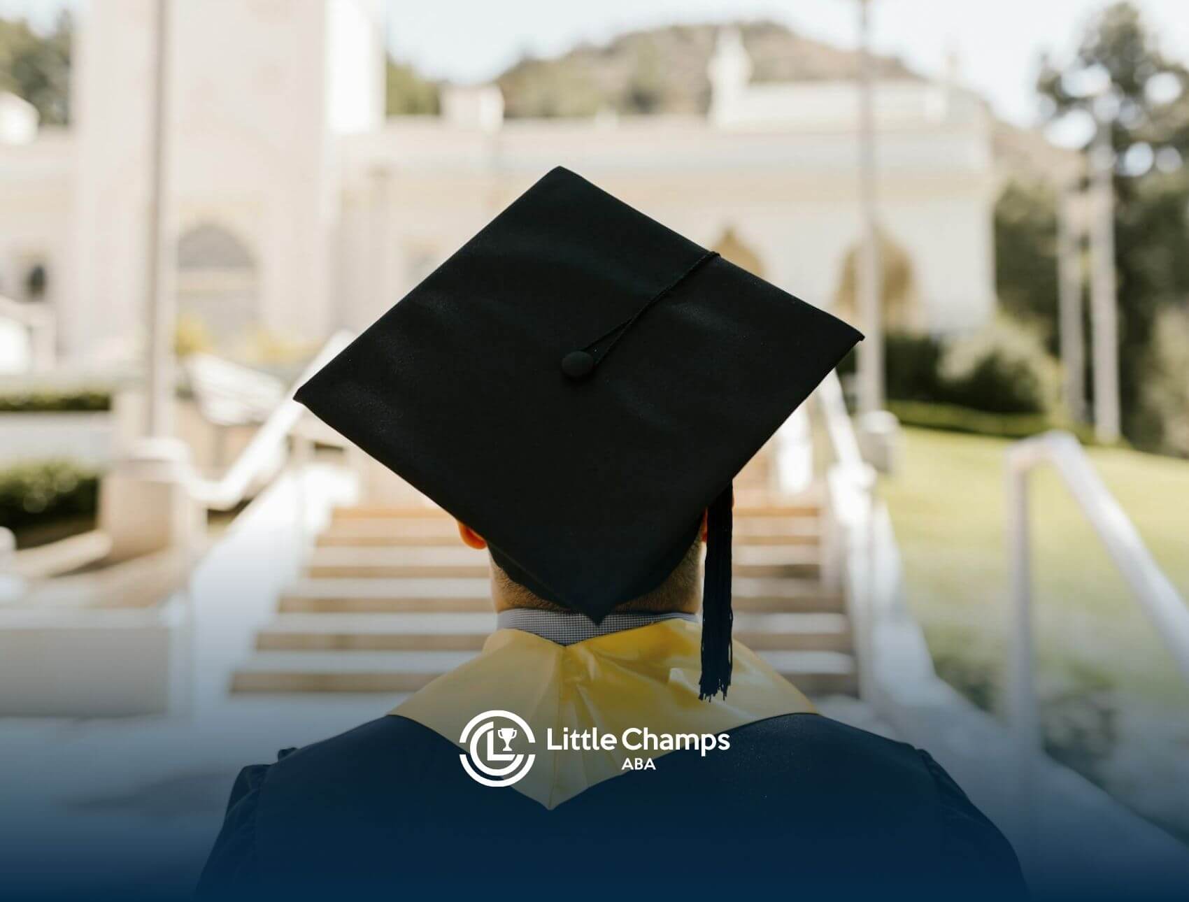 Graduate in cap and gown standing outside, facing steps of a bright building in North Carolina.