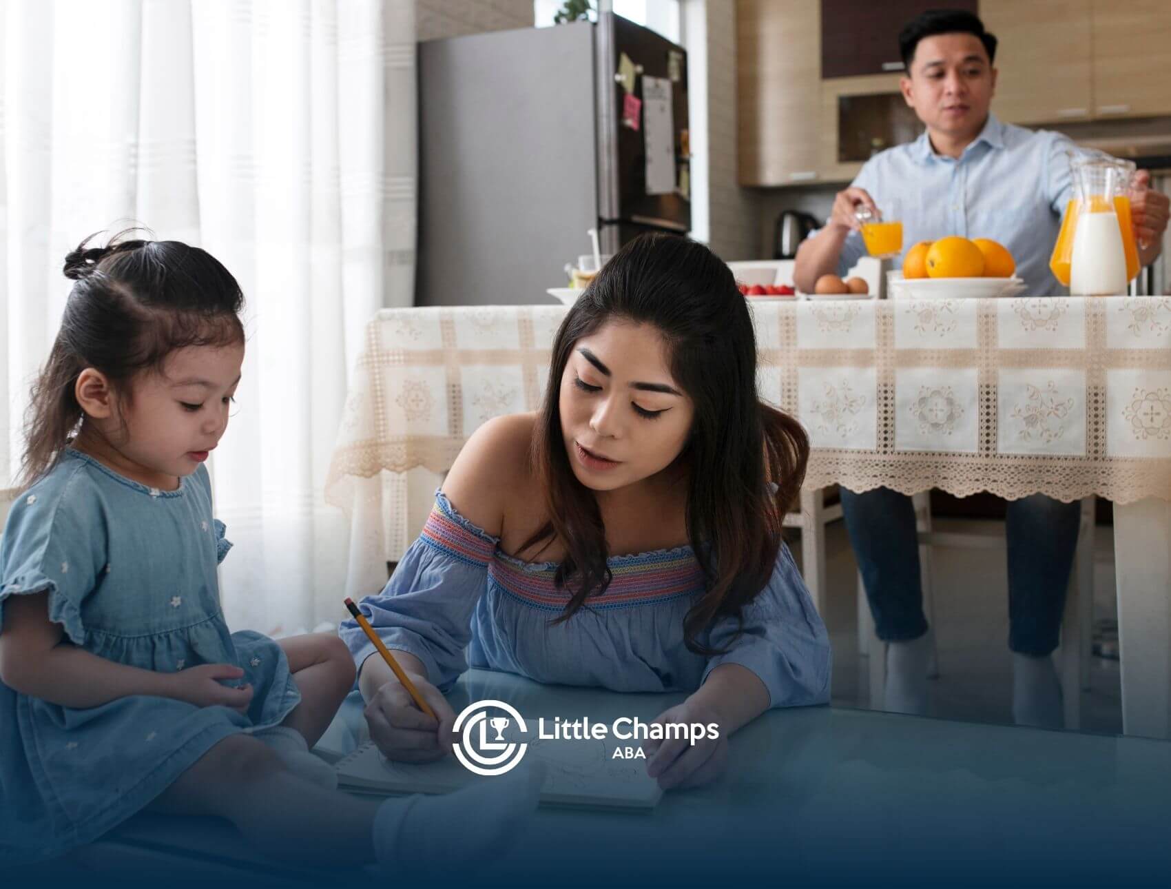 A female ABA therapist and her young autistic child sitting at a table, drawing together in a cozy, well-lit home.